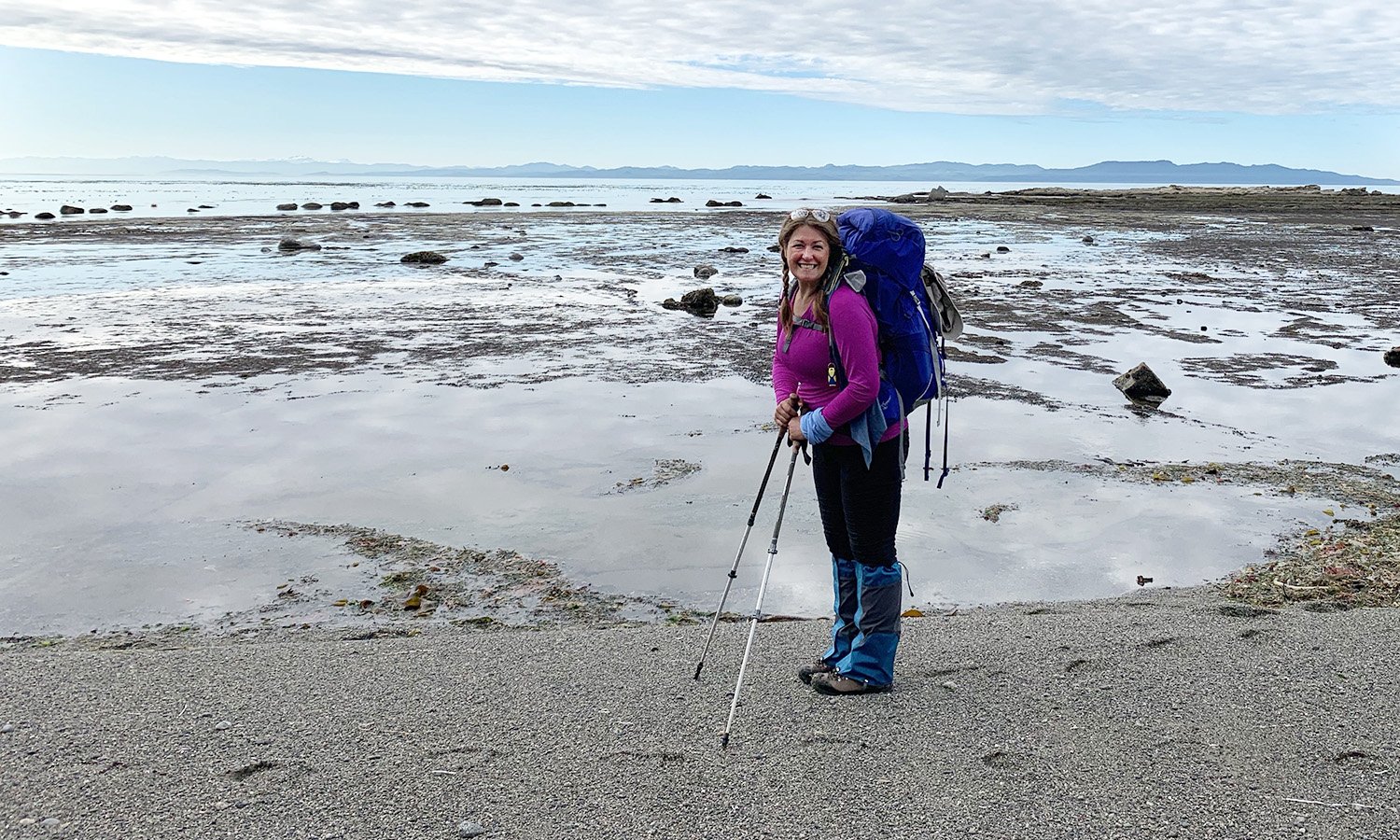 Woman walking by the ocean carrying hiking pack