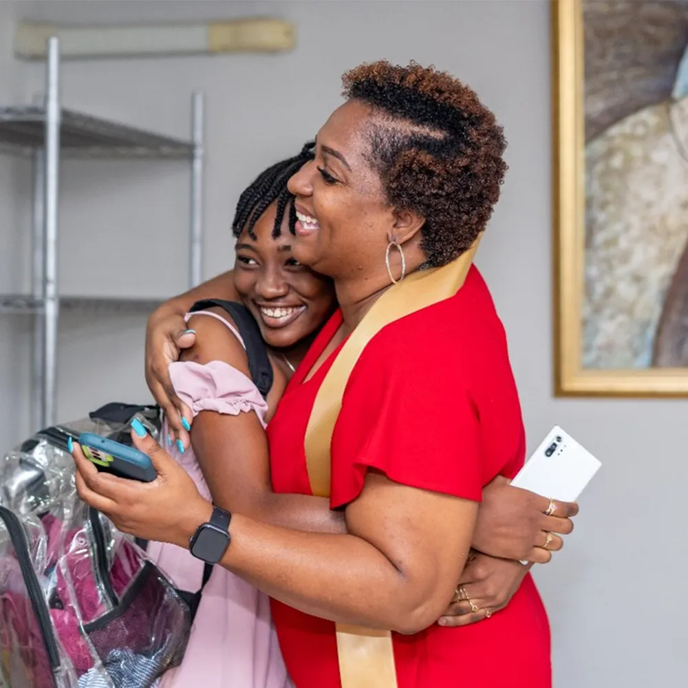 A woman hugging a child while smiling indoors.