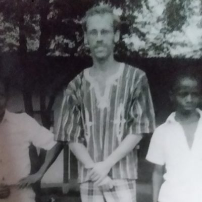 A black and white image of Richard standing with two boys in white shirts