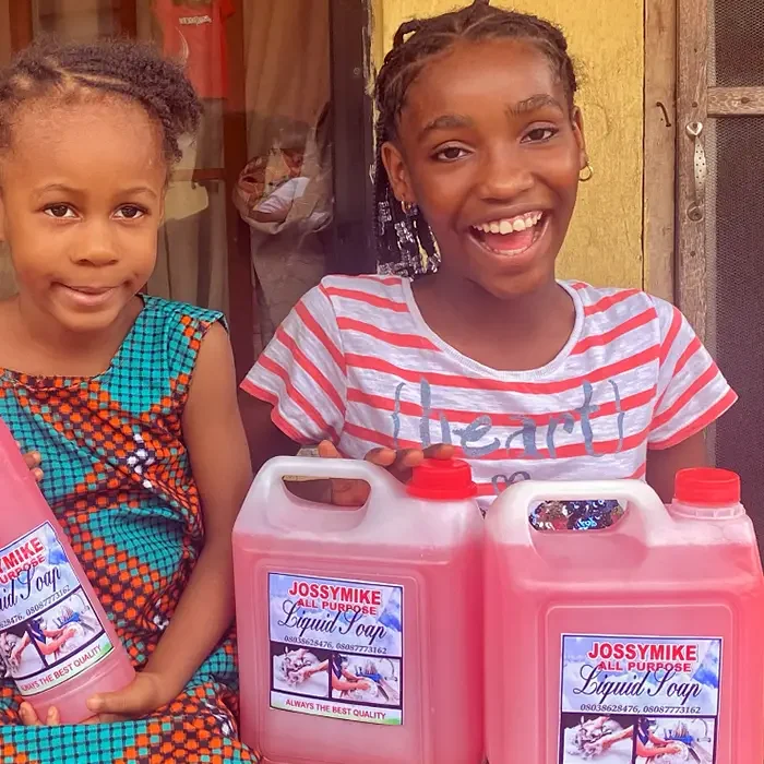 Two smiling children with jugs of Jossymike Soap, supported by Cuso International Nigeria.