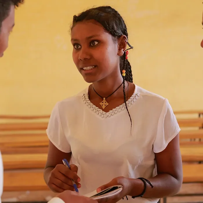 Étudiante parlant à l’intérieur, tenant des notes et s’adressant à un groupe