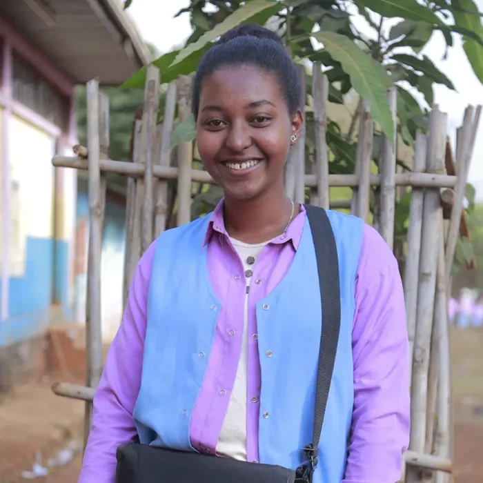 Étudiant souriant debout à l’extérieur avec un sac à dos, regardant la caméra