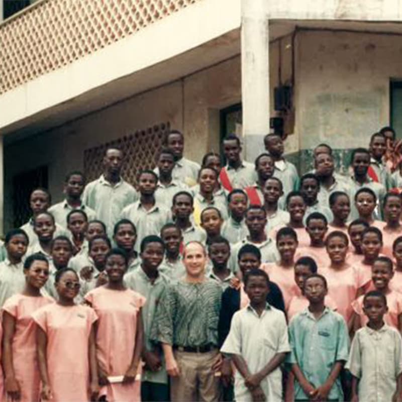 Bob standing infront of a white building with a group of youth