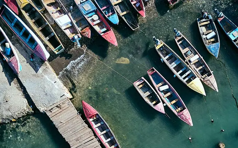 Aerial view of colorful boats moored at a Caribbean dock in clear water.