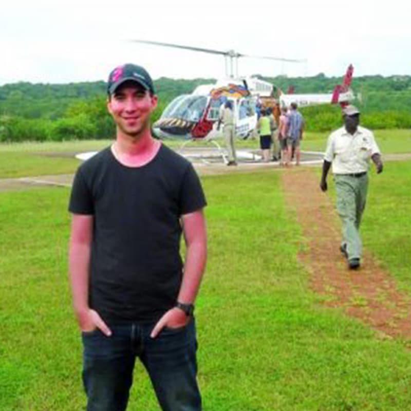 Chris standing in front of a helicopter on green grass