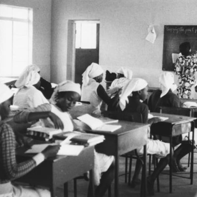 A black and white photo of group of children in a classroom
