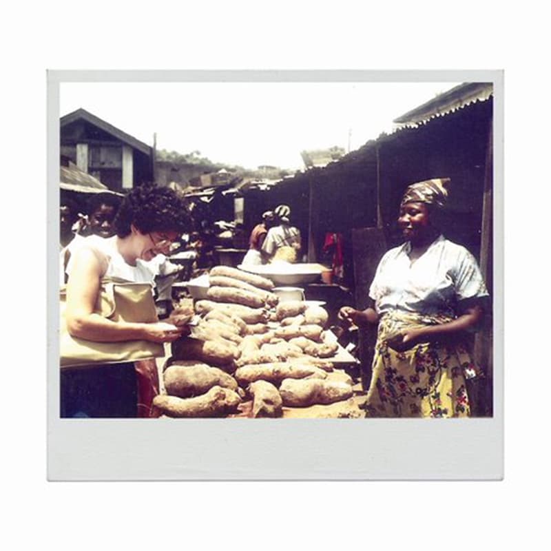 A woman with curly hair buying casava from a market stall
