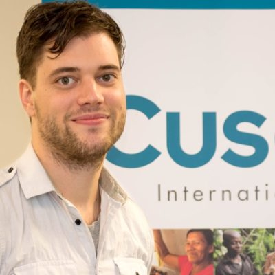 Man smiling in front of Cuso sign