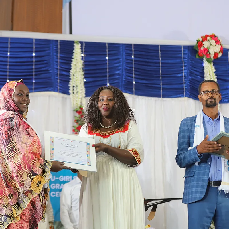 Femme recevant un certificat sur scène lors d’une présentation officielle